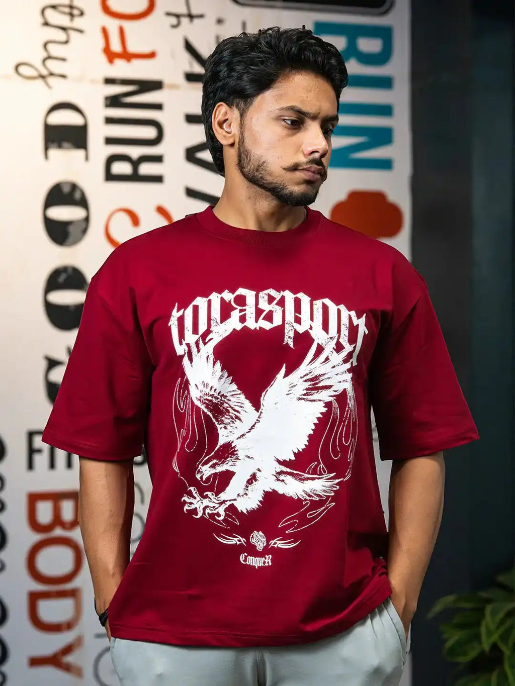 Man wearing maroon gym wear t-shirt with bold eagle print and athletic graphics.