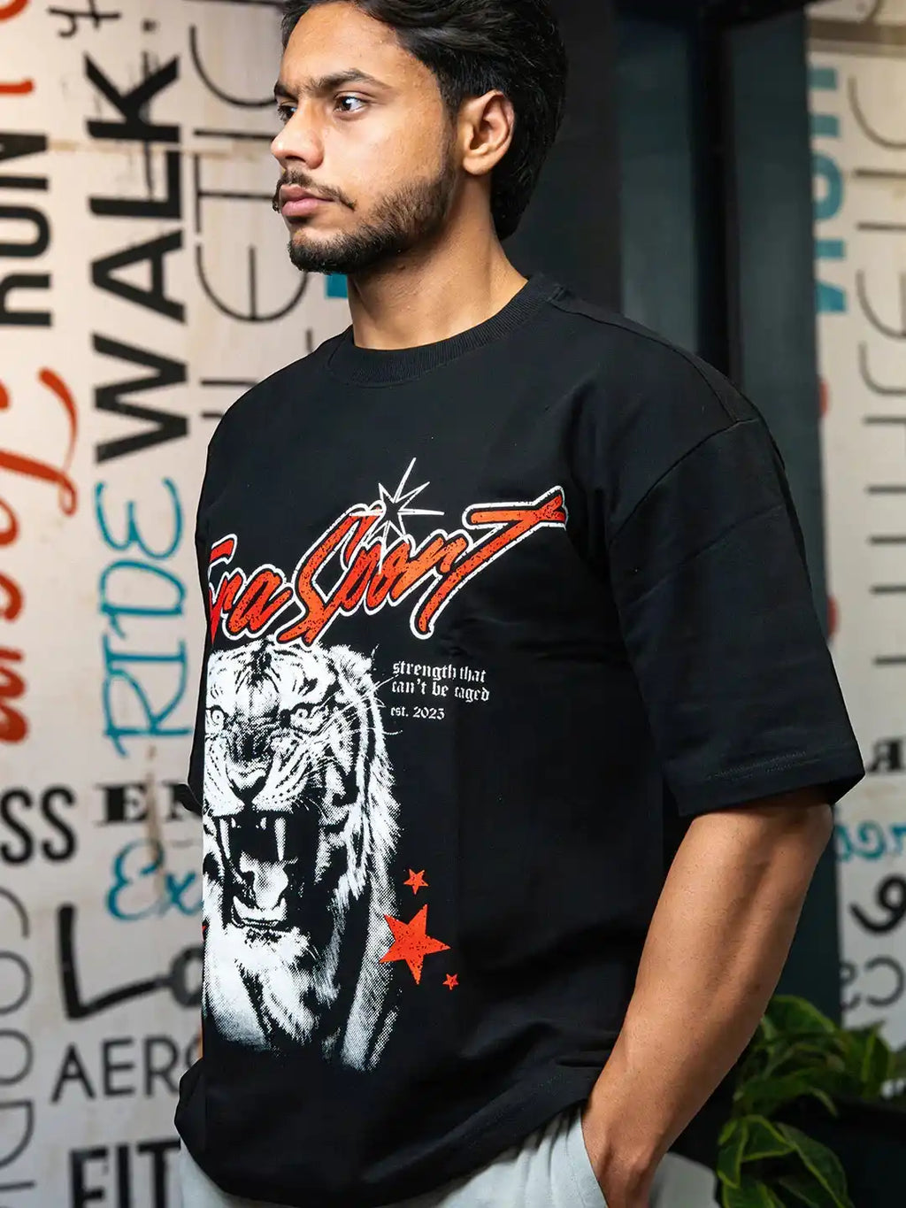 Man in gym wearing black oversized t-shirt with roaring tiger graphic and red stars