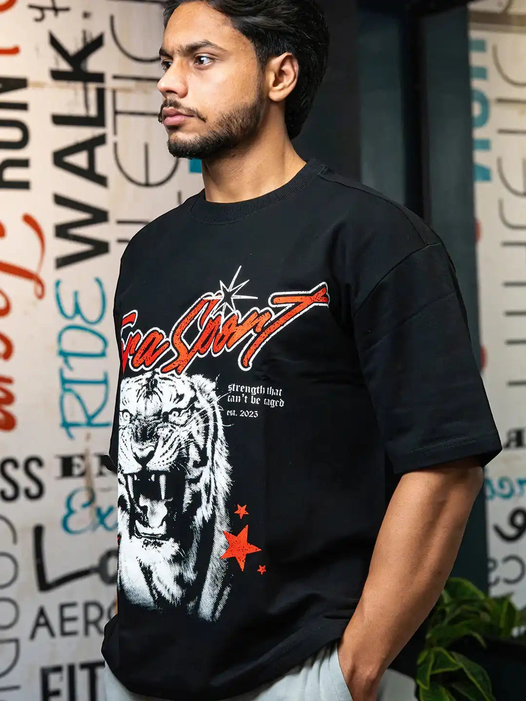 Man in gym wearing black oversized t-shirt with roaring tiger graphic and red stars