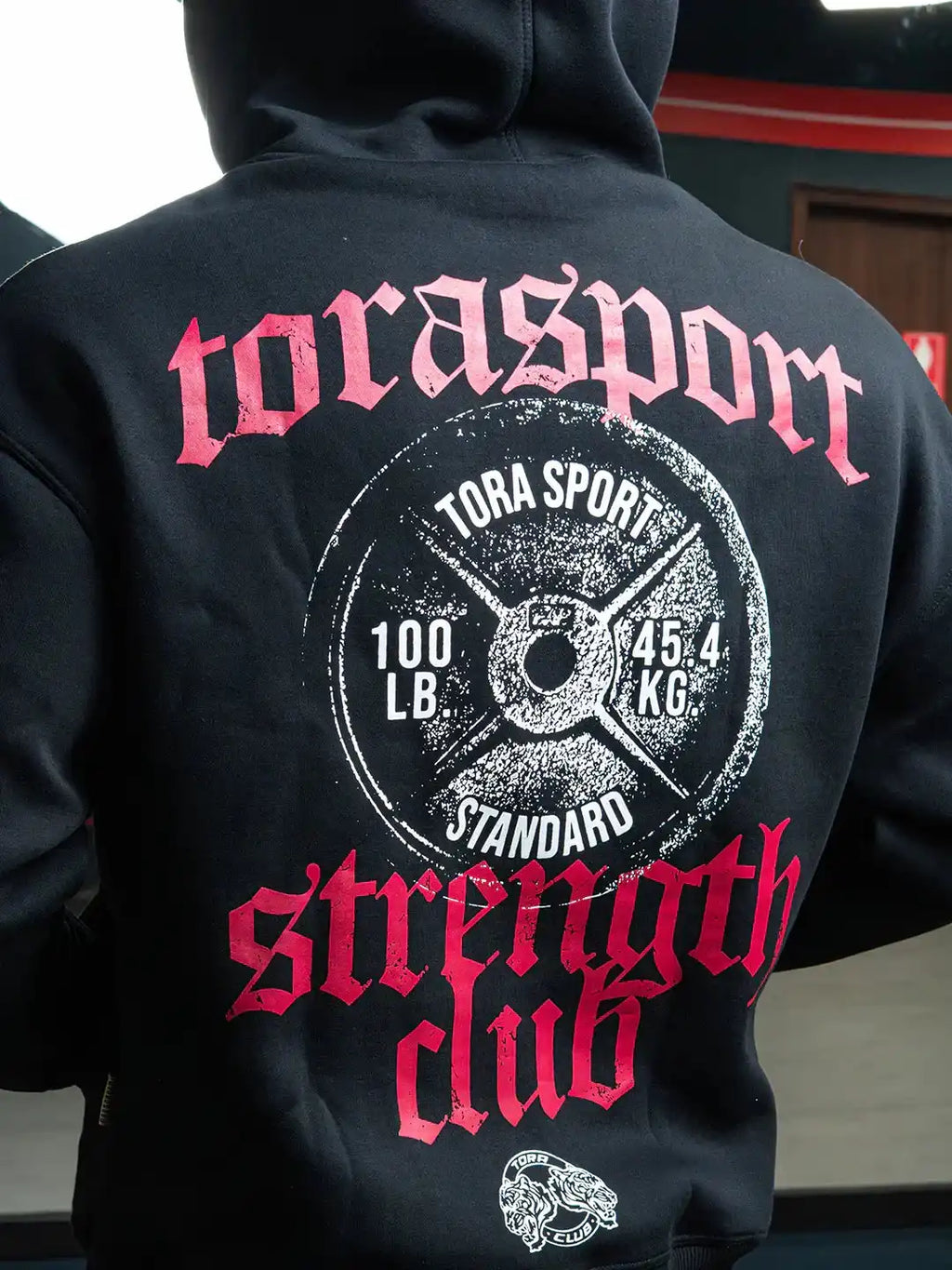 Black gym hoodie with bold 'strength club' graphic, weight plate print, and red lettering.
